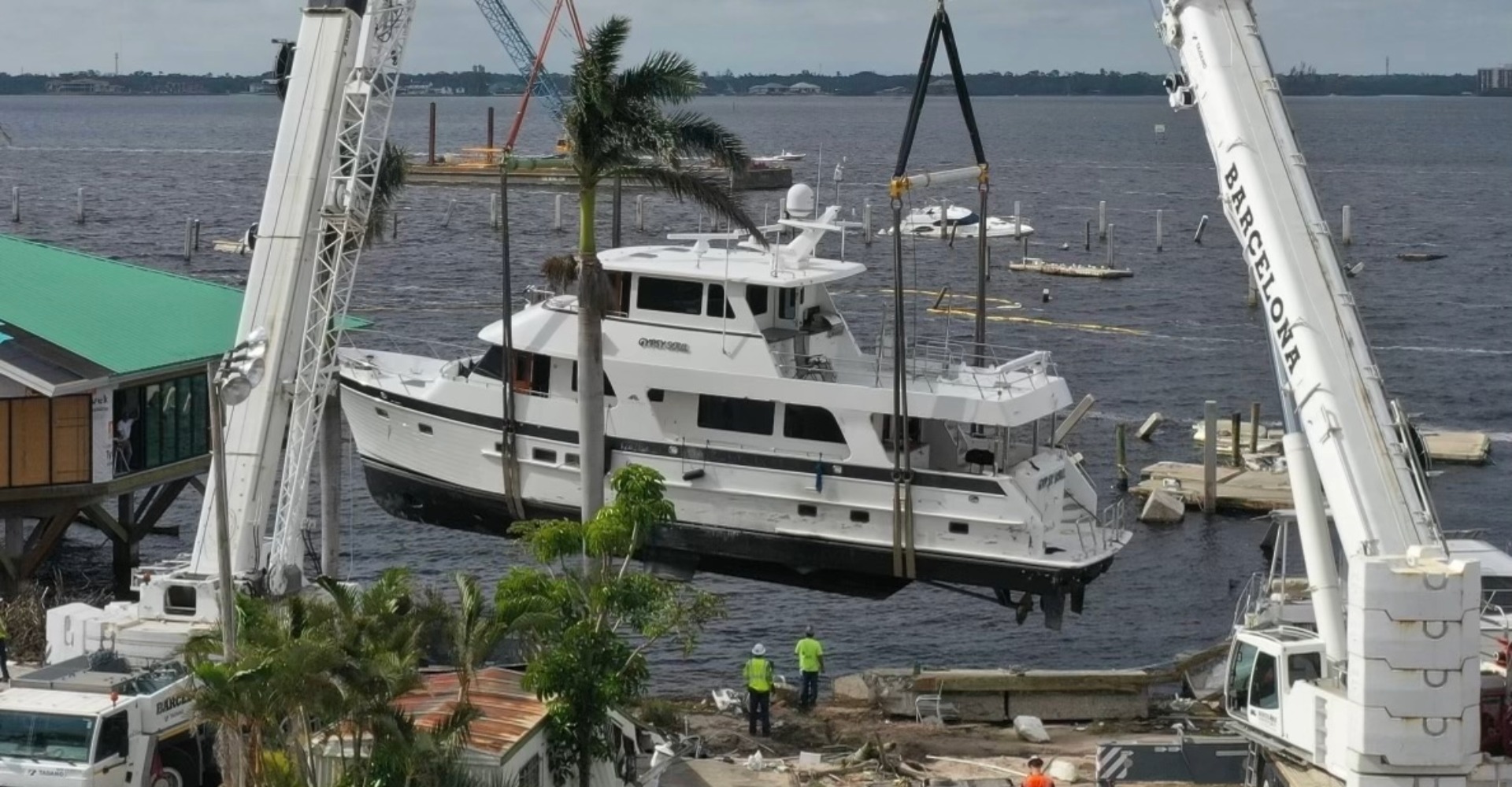 Two cranes lifting yacht